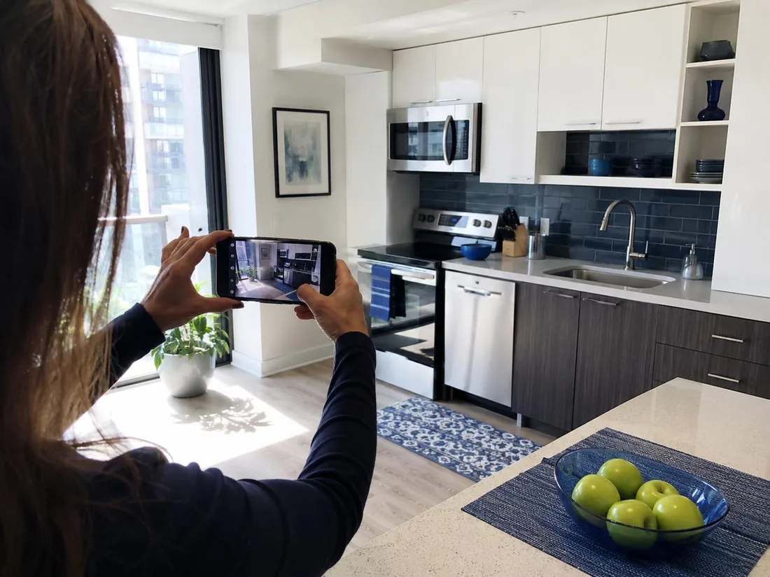 Homeowner using a phone camera to photograph attached condo kitchen finishes for documentation